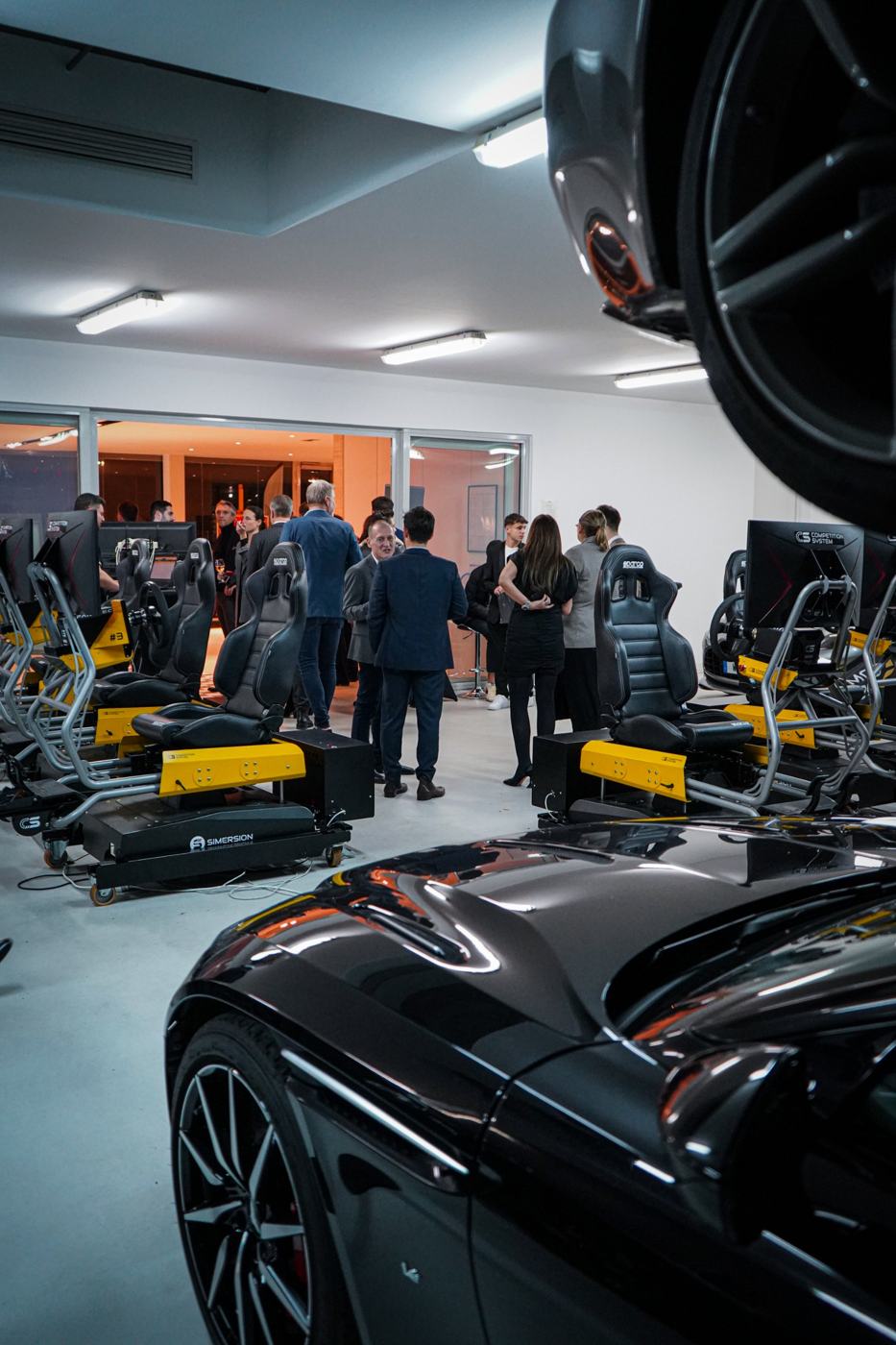 Soirée dans un espace Aston Martin, invités autour des simulateurs